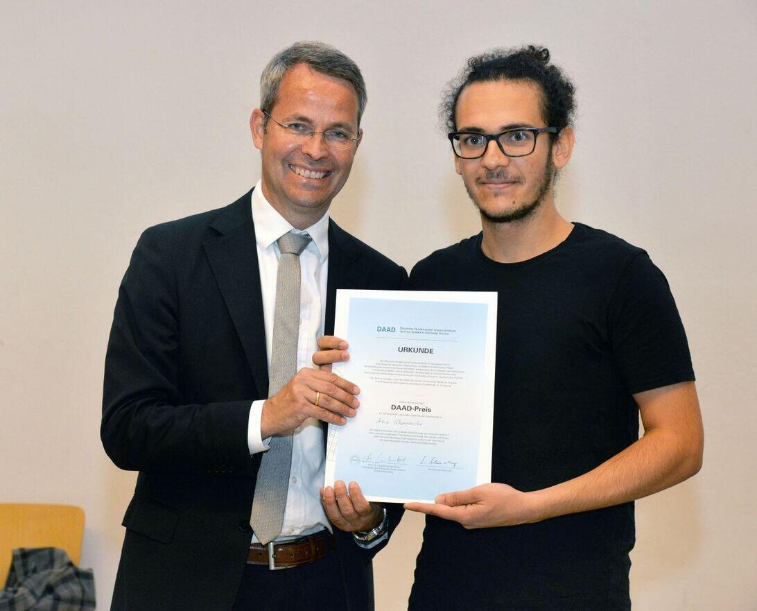 Two people looking at the camera and holding a certificate